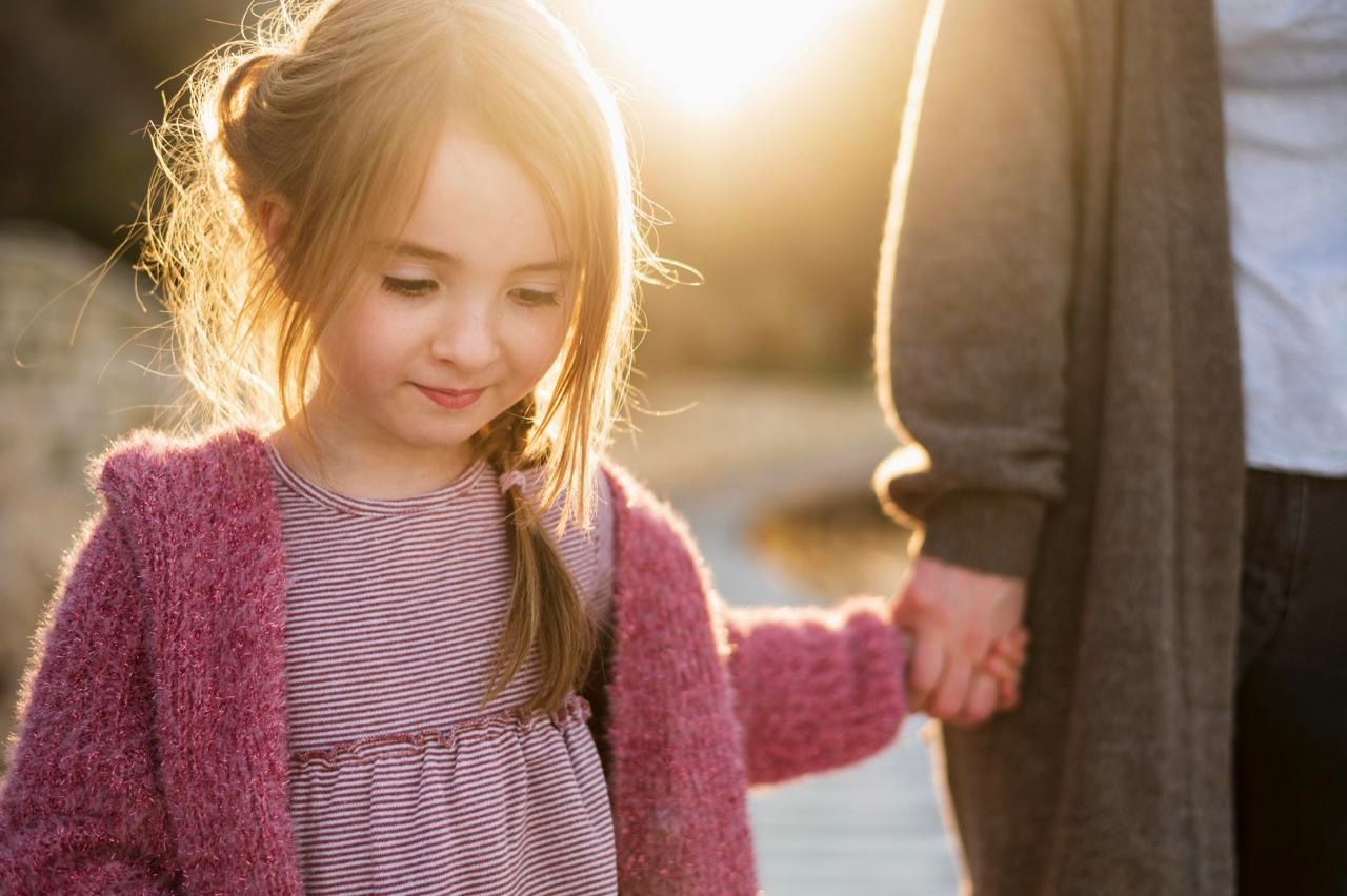 Kind hält die Hand eines Schulbegleiters.